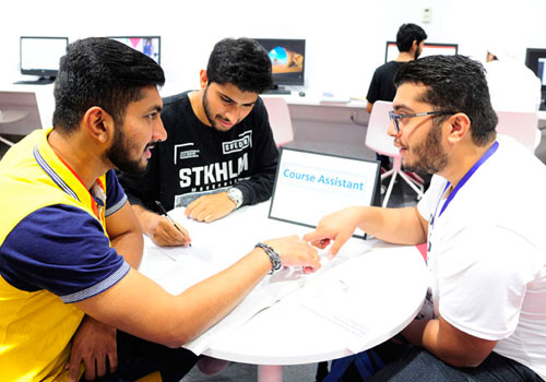 Male students considering pursuing undergraduate courses in the UAE at Abu Dhabi University speaking with a Course Assistant