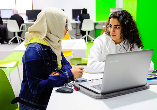 طالبتان أمام كمبيوتر يتحدثان عن تخصصات الجامعة في جامعة أبوظبي