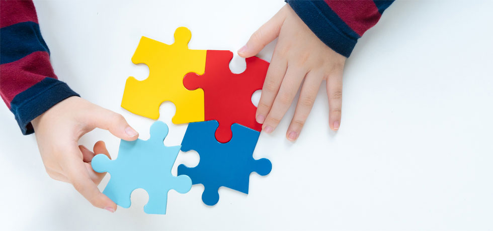Hands of a child diagnosed with Autism Spectrum Disorder playing with puzzles