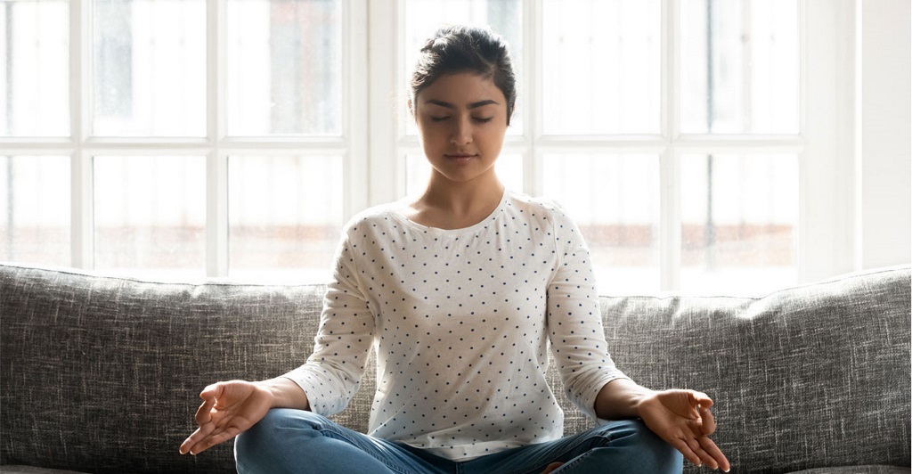 Female student practicing meditating to reduce stress