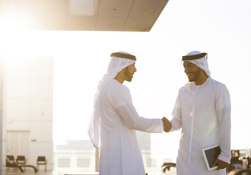 MBA in Abu Dhabi students standing outside shaking hands in the sun