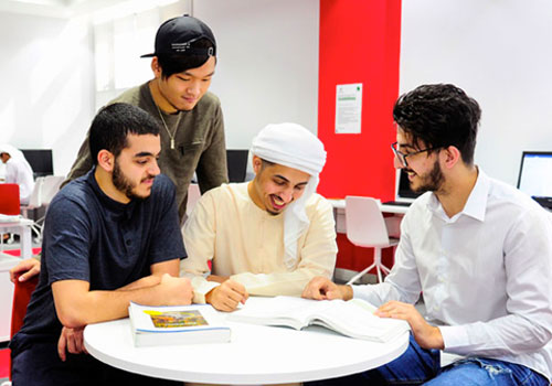 Four male students looking through a Biomedical Engineering textbook