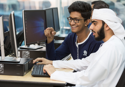 Two Bachelor of Science in Information Technology students working on a computer