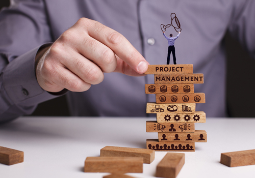 Masters in Project Management student stacking wooden building blocks