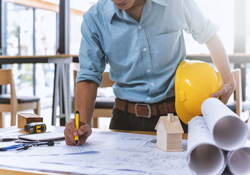 A man using skills learned from his Civil Engineering Masters scholarship inspecting engineering plans