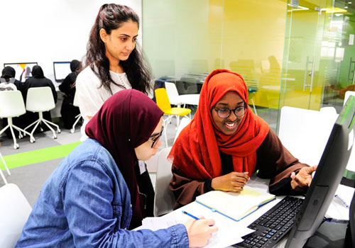 3 Female IT Master's students discussing a project on their laptops