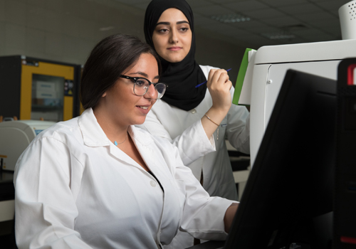 Two female students completing their Bachelor of Environmental Health are analyzing data in a lab