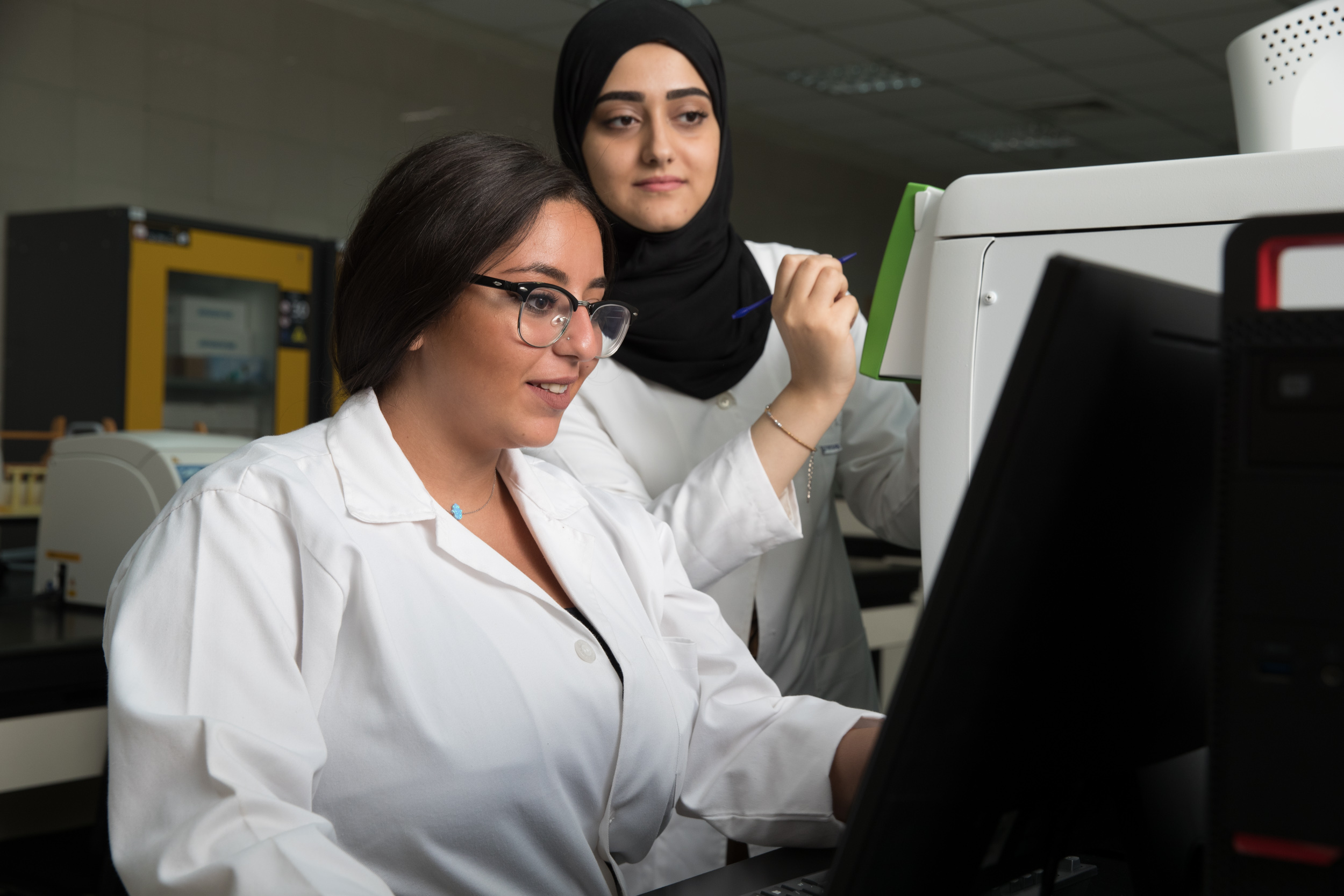 Two female students doing their BSc Environmental Health are  looking at data on a computer screen