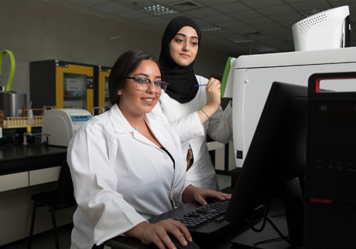 Two female students studying their Bachelor's Degree in Nutrition and Dietetics analysing data in a lab