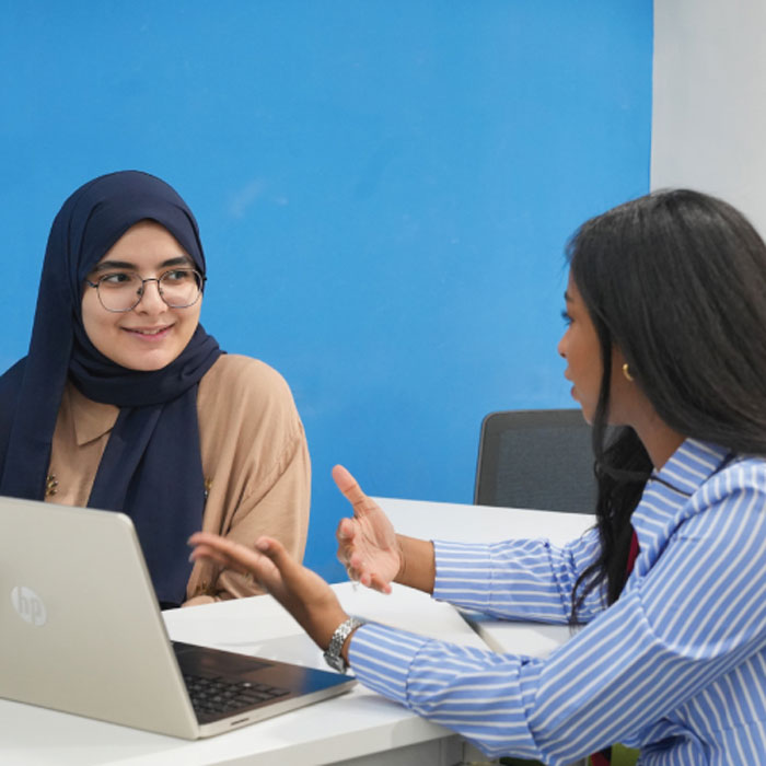 Group of professionals in formal attire collaborating around a laptop in a bright modern office.